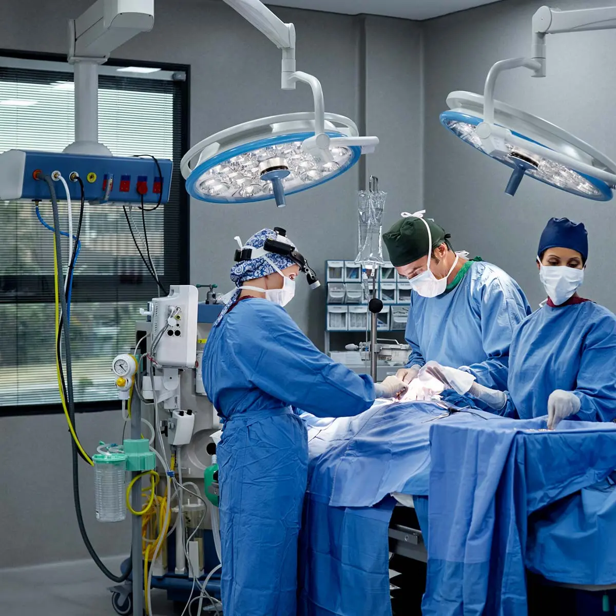 Operating room full of surgeons and nurses working with connected medical saw.