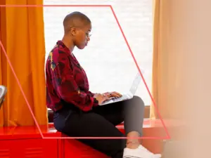 Woman seated on counter with laptop.