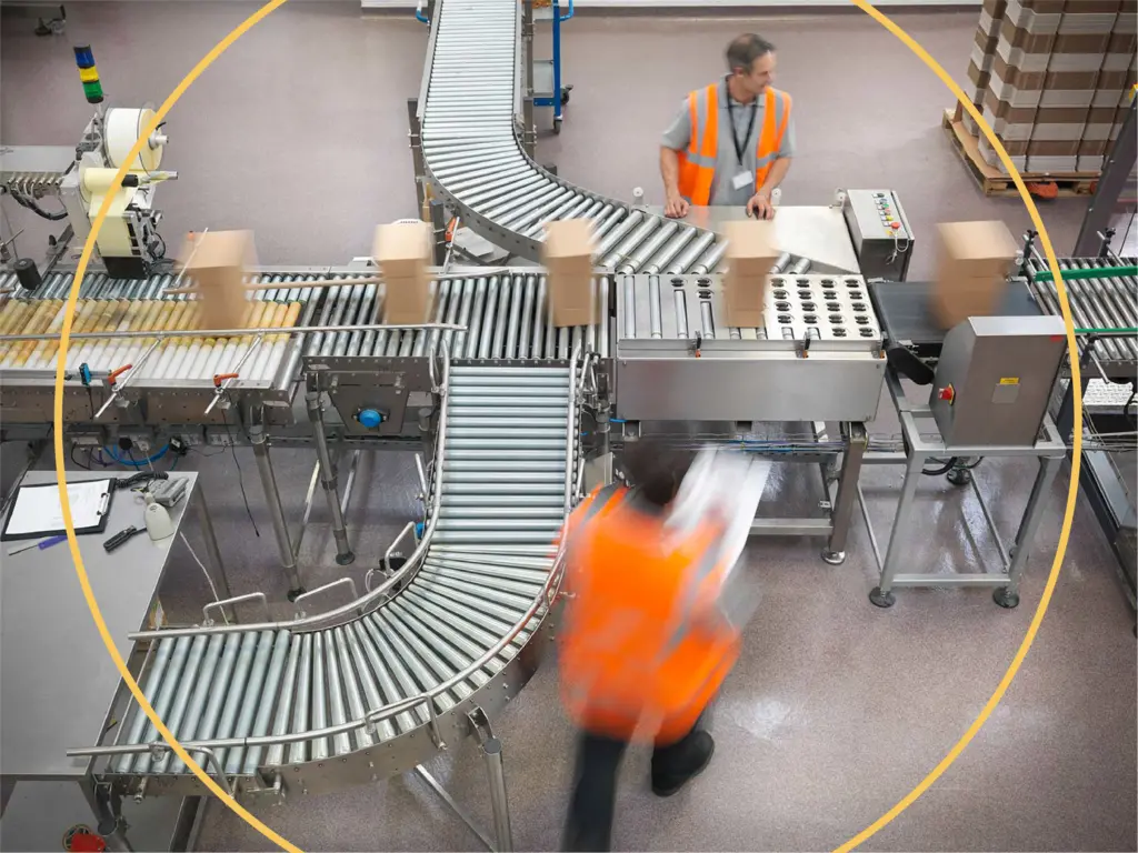 Factory workers walking around a conveyer belt with packages going through