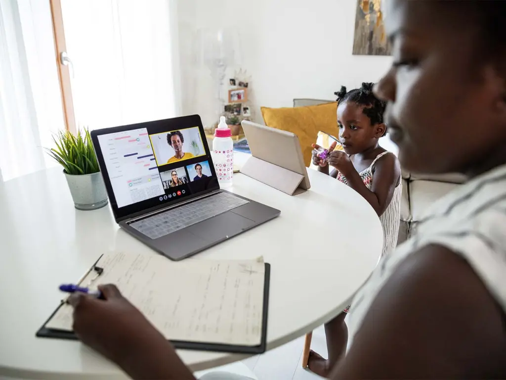 Mother working remotely while caring for children at the table