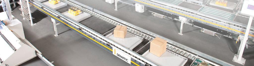 Image of a conveyor belt with boxes on it. Sign on the side reads “Dematic”.
