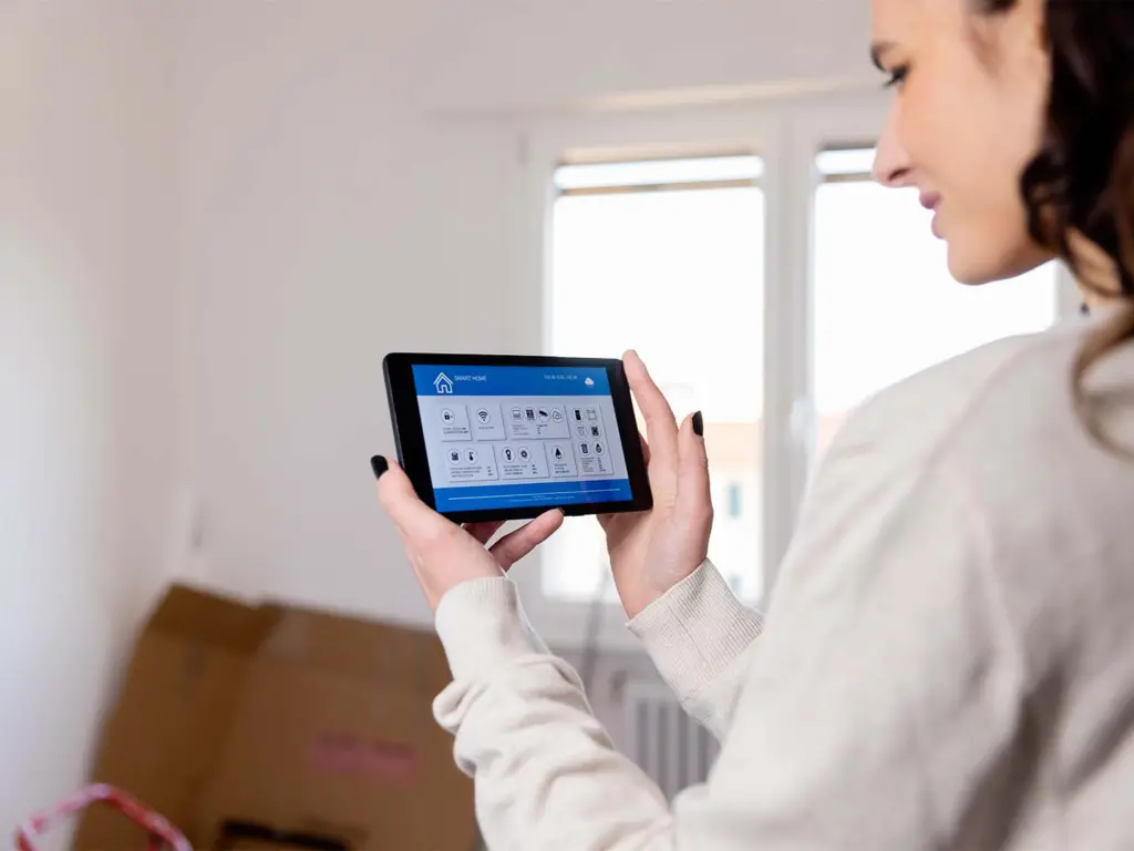 An unrecognizable female new homeowner uses an interactive smart home app