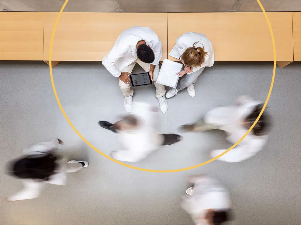 Medical professionals walking in the corridor and looking over patient charts.