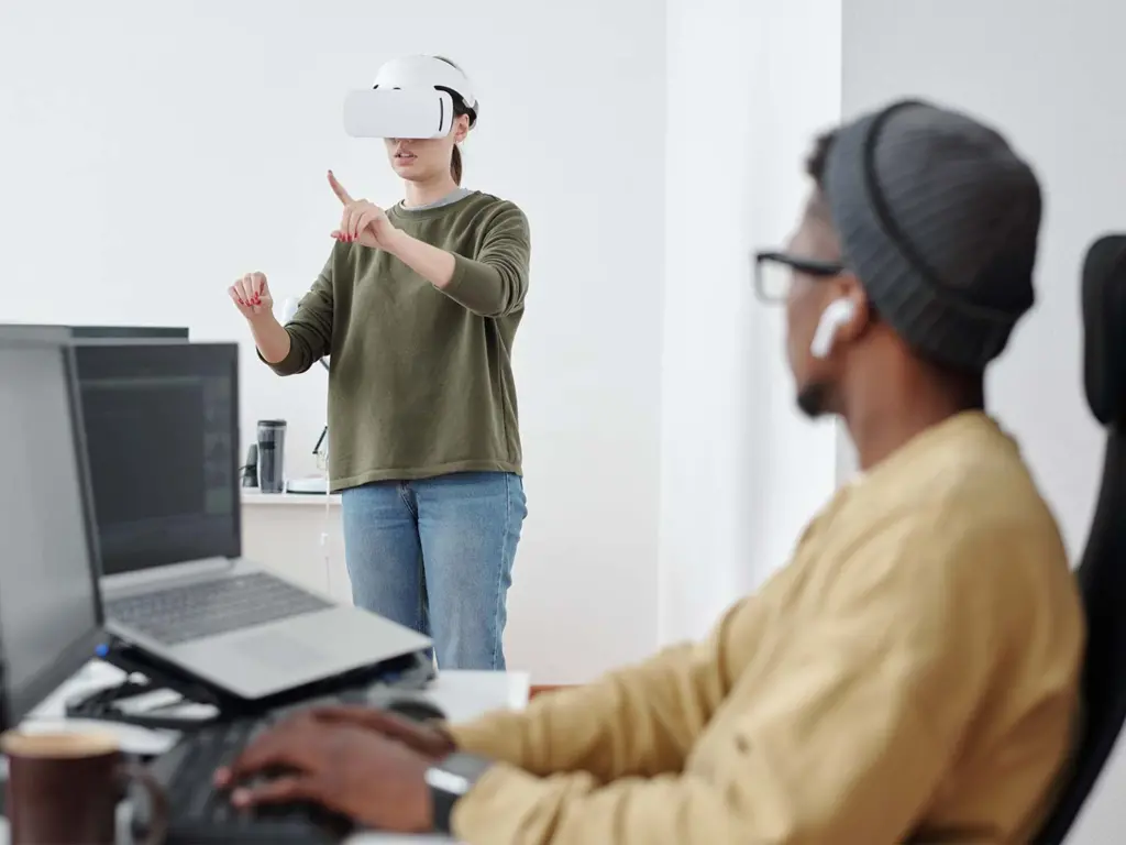 Contemporary young businesswoman in vr headset making virtual presentation in front of male colleague decoding data