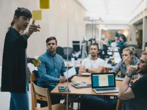 Computer programmer explaining IoT product roadmap while giving presentation to colleagues in office.