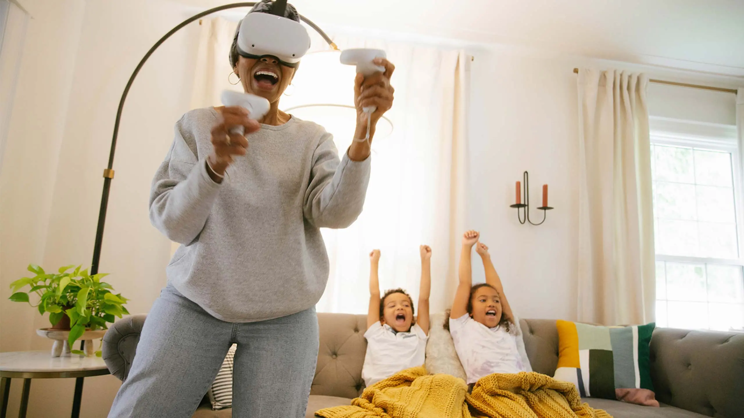 Grandchildren cheering on grandparent while playing with virtual reality (VR) headset