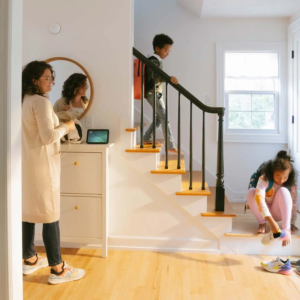 Family getting ready to head out the door. Mom interacting with smart connected product home device.