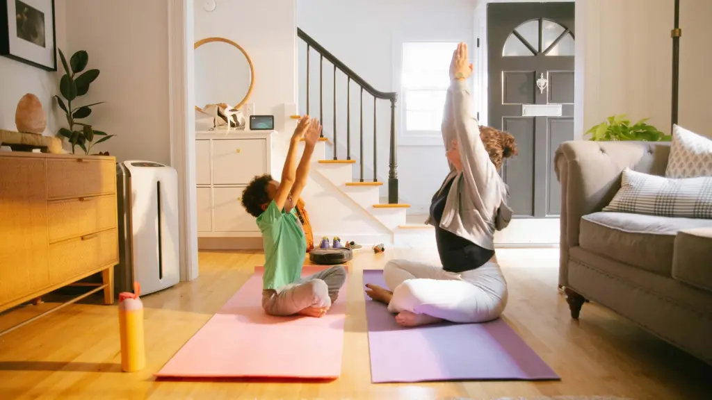 Mother and son stretching surrounded by connected products, smart vacuum, smart home hub, and air conditioner.