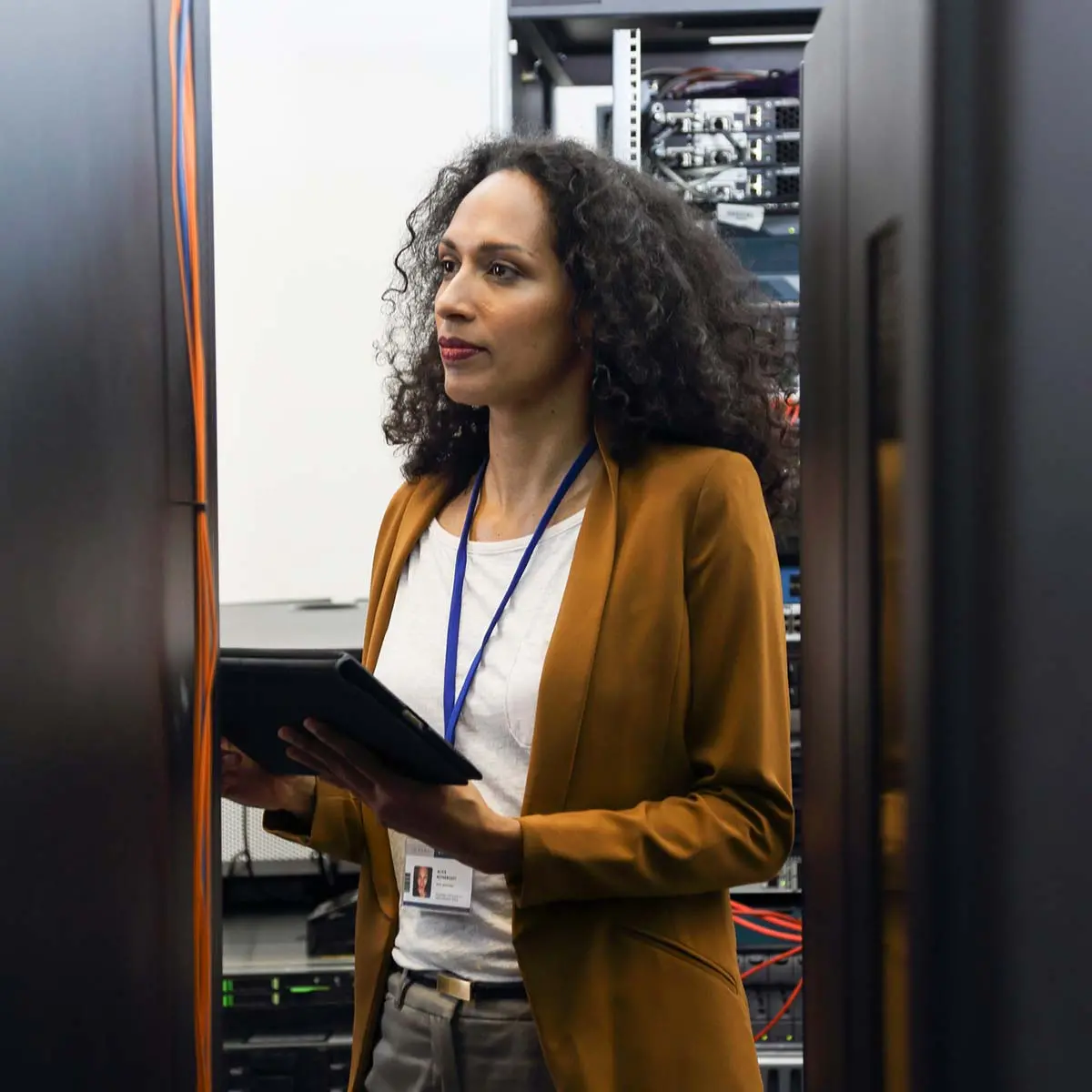 Woman in data center programing mainframe on a digital tablet.