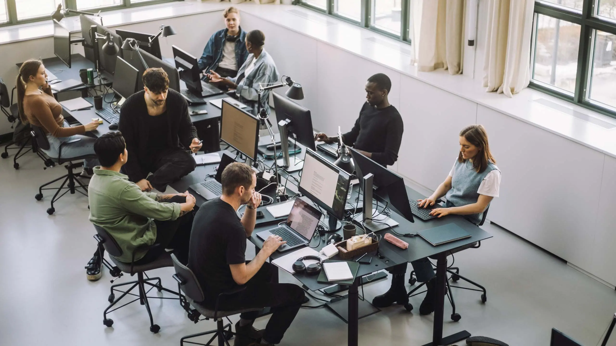 High angle view of male and female programmers working on computers at desk in office