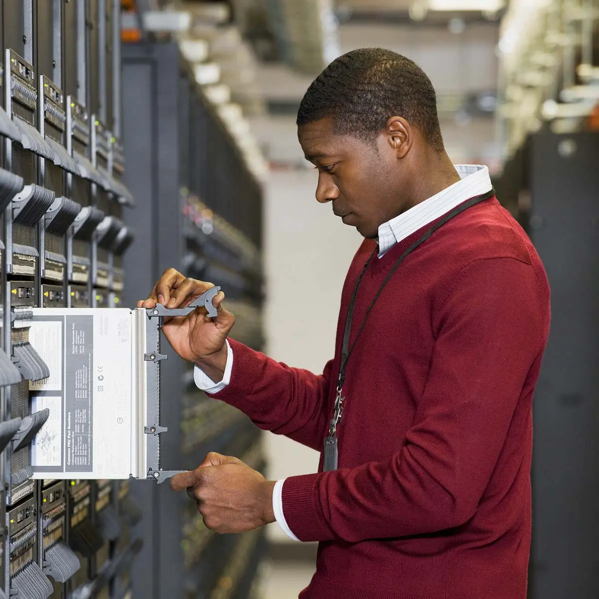 IT worker in red sweater removing a server