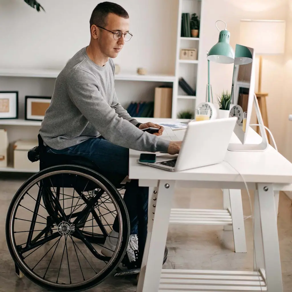 Man in a wheelchair working at home office