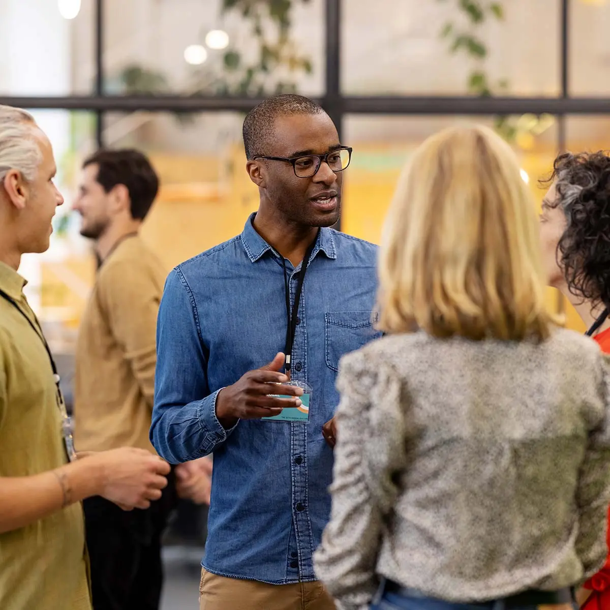 Group of multiracial businesspeople standing in lobby discussing on the edges of a start up conference. Business men and women talking before an event in office.