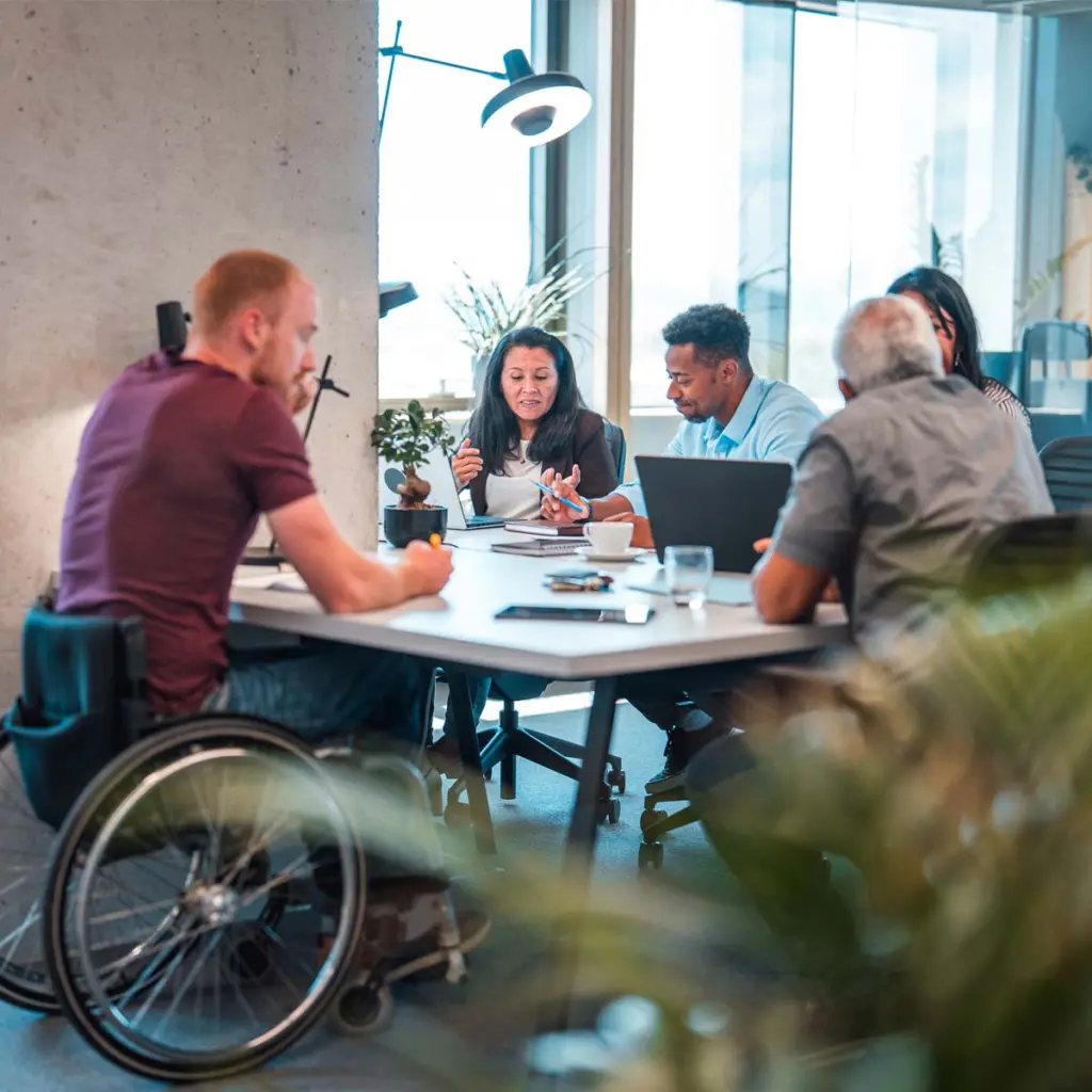 Coworkers at an open concept office. They are seated in comfortable chairs as they work using laptops.