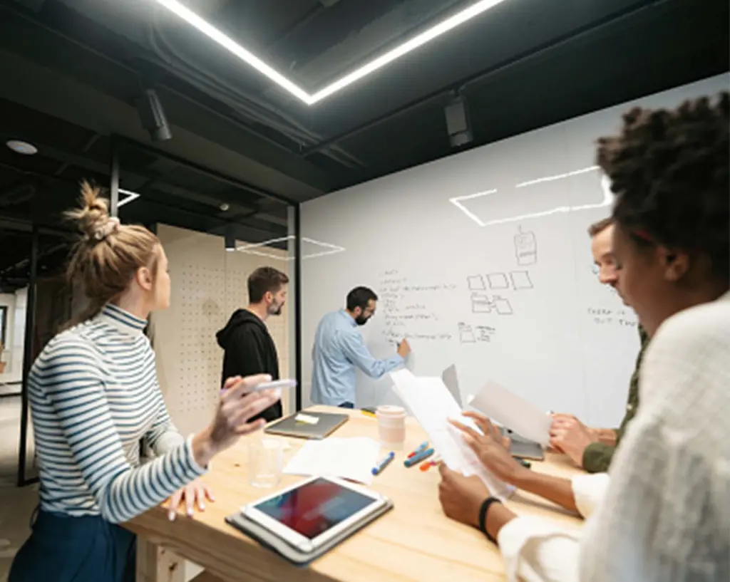 Photo of a group of coworkers following a presentation and participating in a meeting.