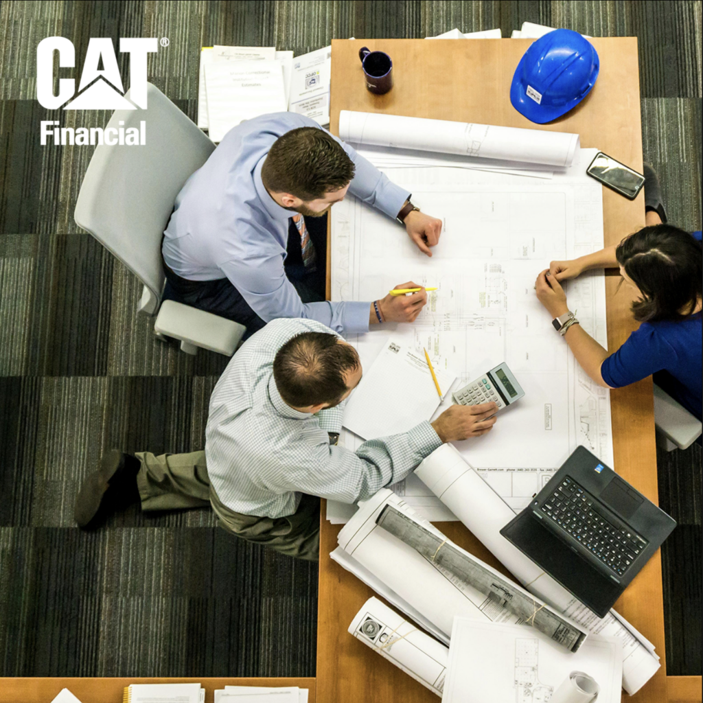 Group of architects meeting around a table covered in blueprints with the CAT Financial logo in the top left corner