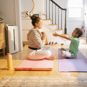 Mother and son sitting on living room floor practicing yoga next to a connected air filtration system